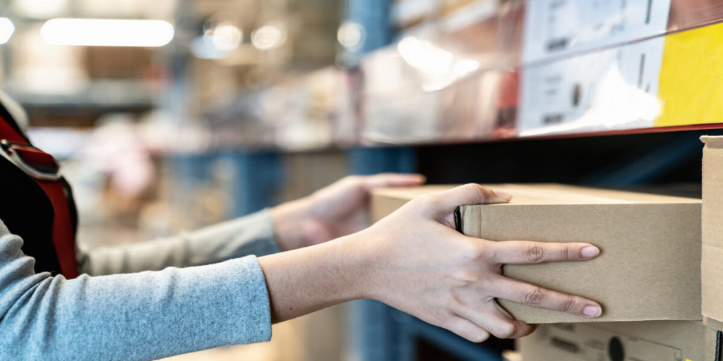 Asian woman's hand shopping in self picking box,package and collect product from shelf,rack in warehouse,store.Worker shipping and delivery packaging business concept with copy space.Courier shipment.